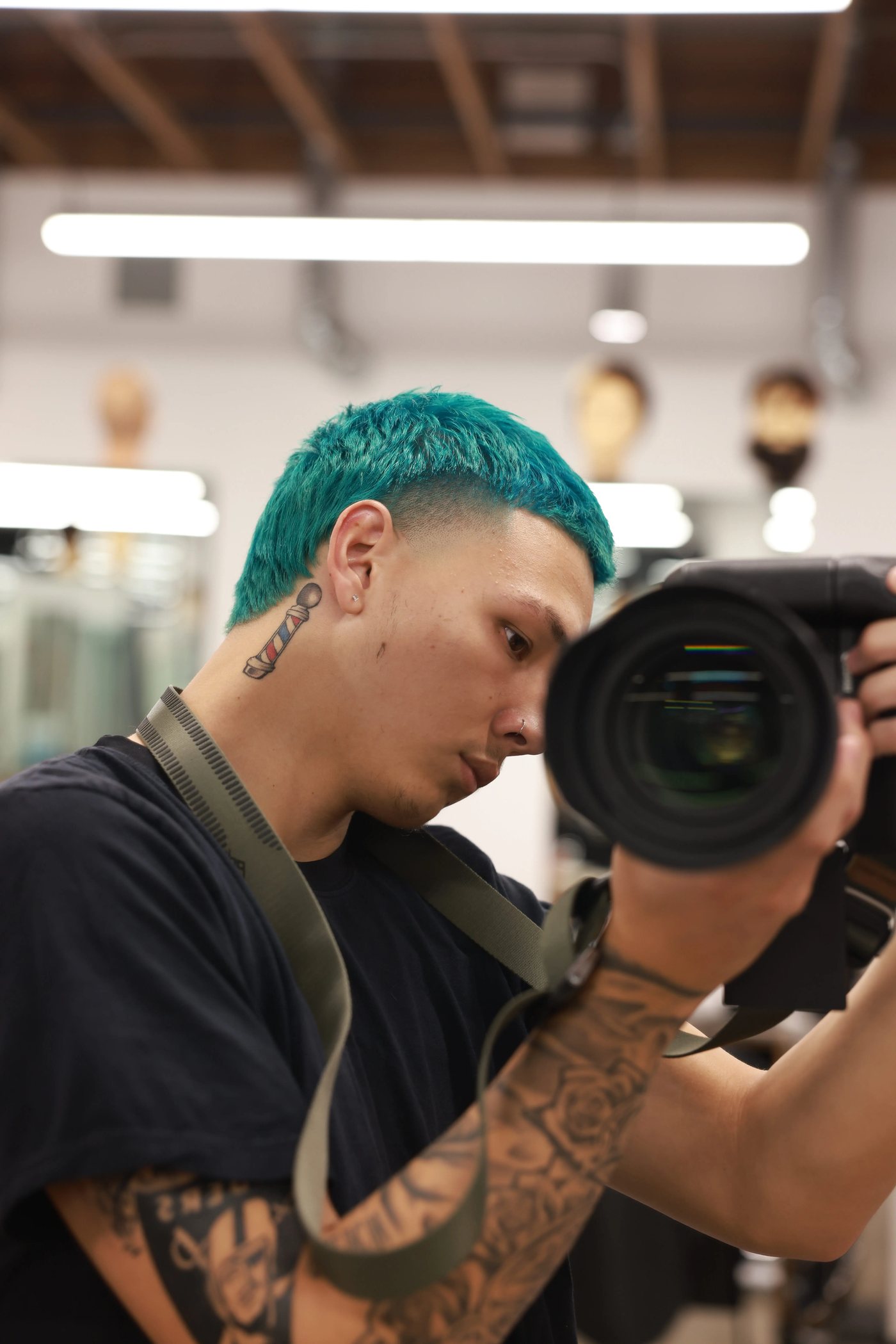 Portrait of Jeremiah, known as YeeBlendz, holding a camera inside the barbershop