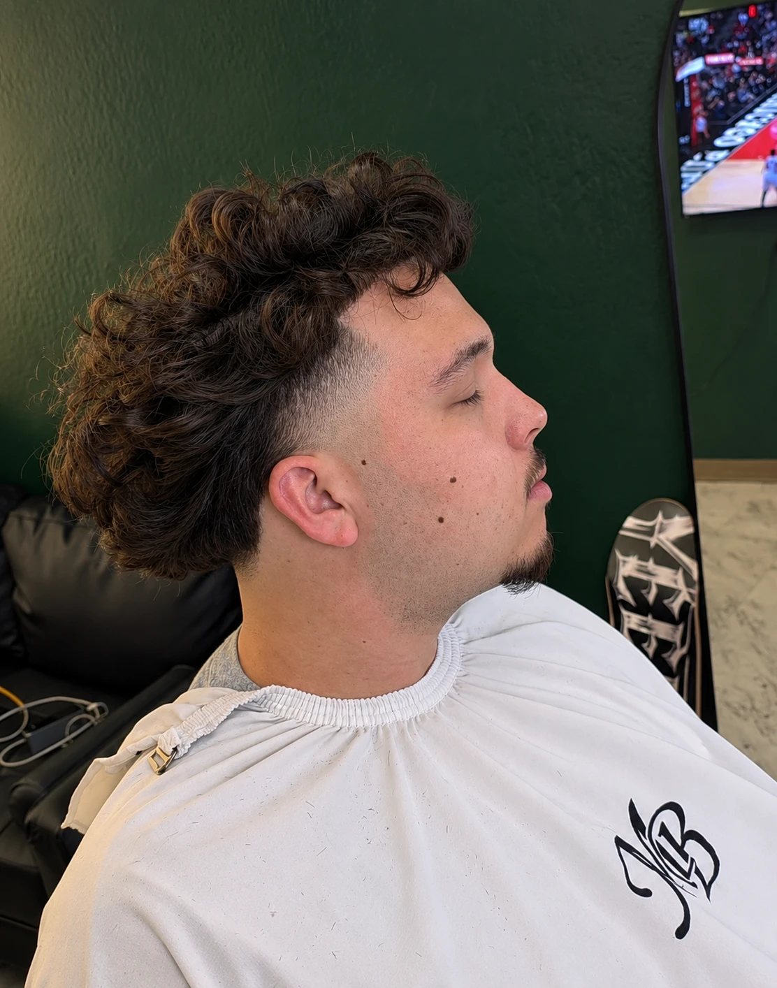 Curly top with a low taper and a clean beard line